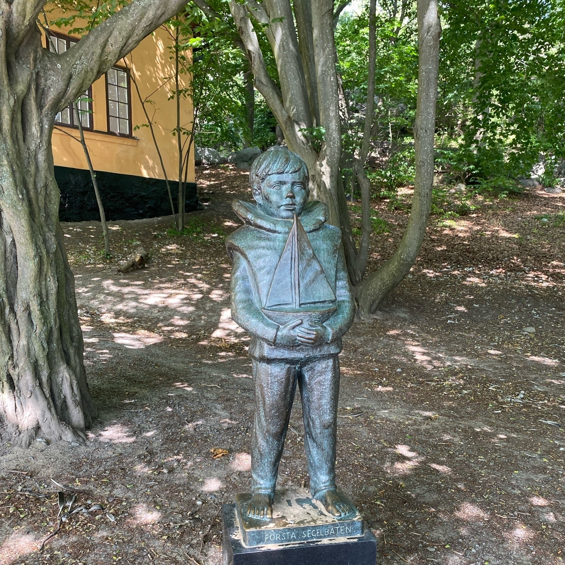 bronze sculpture in Stockholm park of a boy holding a toy boat